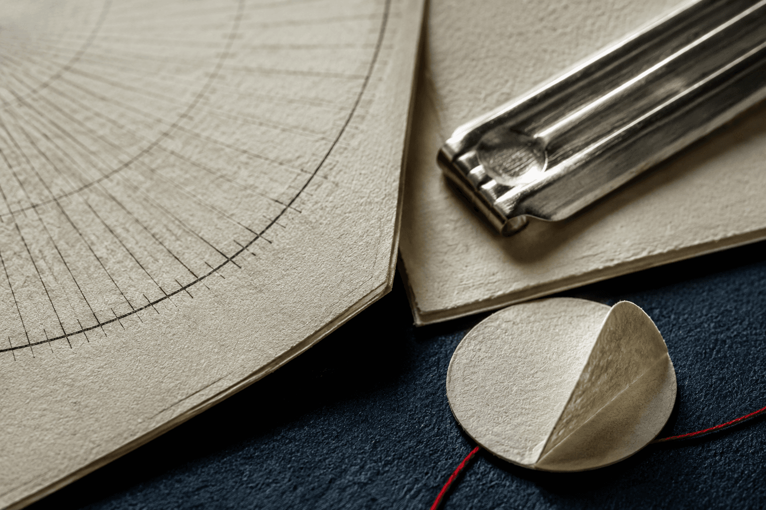 Macro detail of cream planning paper, a radial dial page, a peeled bearing label and a steel clip